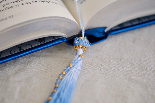 Blue beaded bookmark on an open book with a beige background